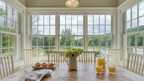 A dining area with a wooden table, white chairs, a pitcher of water, and a tray of muffins. - Secluded Estate Optional Guest House, Pond, Playroom, Gym & Theater Sunny Pond by Avantstay (Austerlitz)