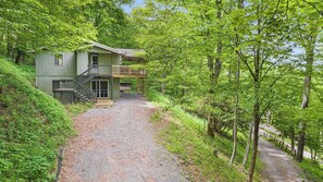 Ein Haus mit Veranda, Treppe und einem von Bäumen gesäumten Schotterweg.