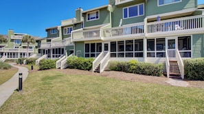 A multi-story residential building with balconies, a pathway, and a well-maintained lawn. - 3C Mariners Walk by Avantstay Beach & Pool Access, Enclosed Porch (Isle of Palms)