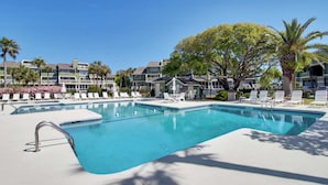 A rectangular swimming pool with a metal ladder, surrounded by white lounge chairs and umbrellas. - 3C Mariners Walk by Avantstay Beach & Pool Access, Enclosed Porch (Isle of Palms)