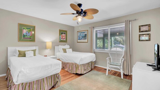 A hotel room with two beds, a ceiling fan, a window with blinds, a chair, and a TV. - 3C Mariners Walk by Avantstay Beach & Pool Access, Enclosed Porch (Isle of Palms)