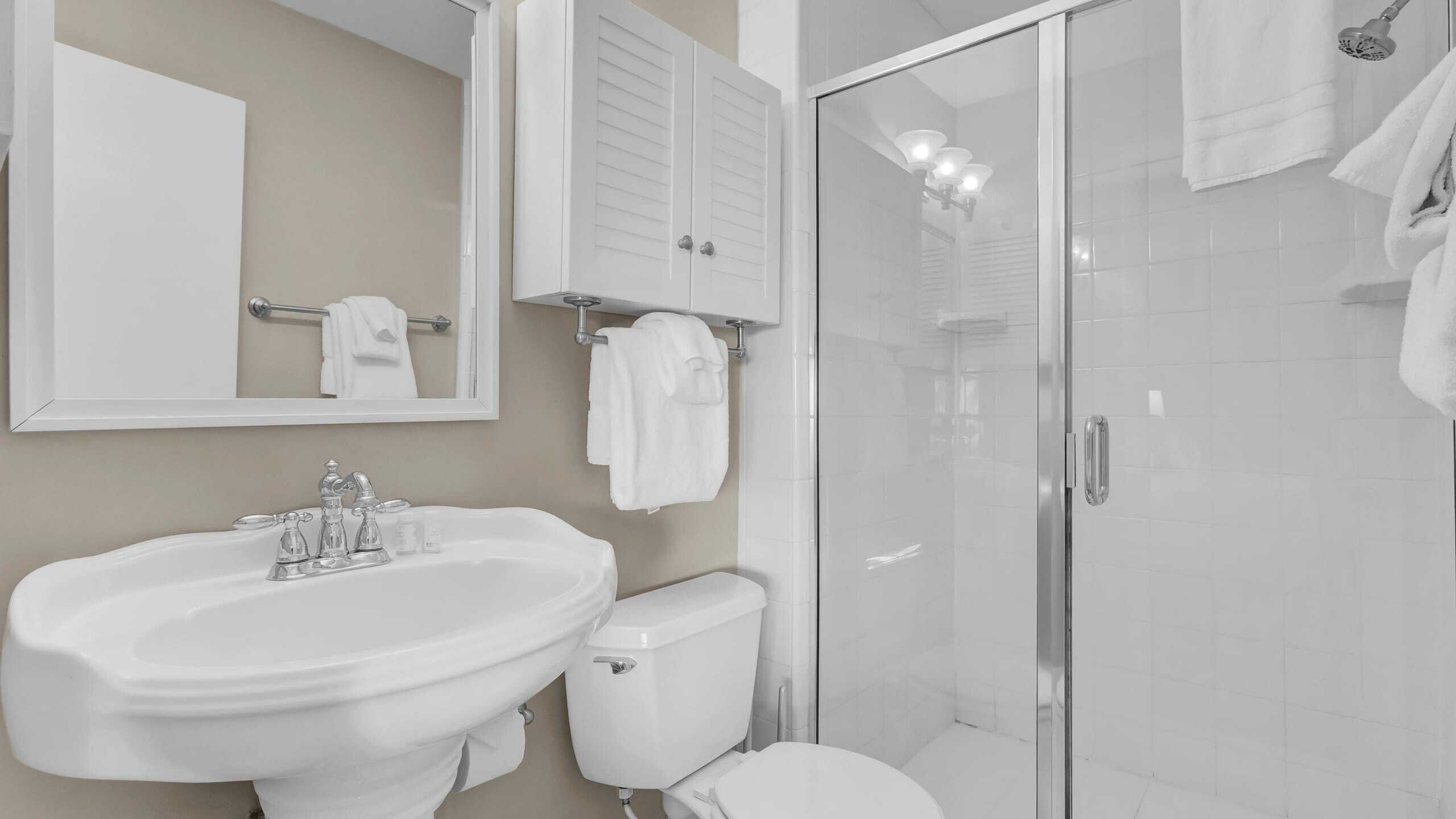 Une salle de bain équipée d’un lavabo, de toilettes et d’une douche à parois en verre.