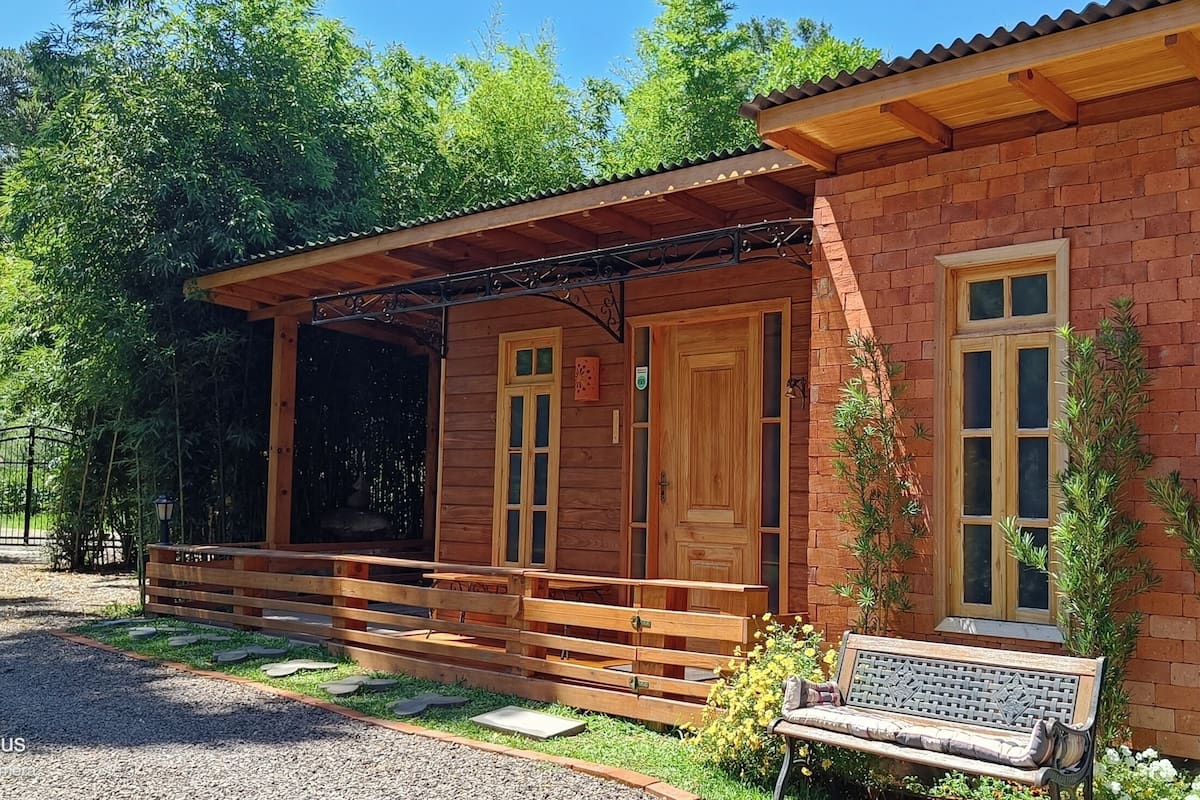 Eine Holzhütte mit Veranda, einem Schotterweg und einem Holzzaun.