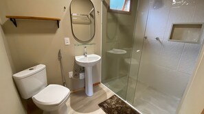 Un bagno con il water, un lavandino e una cabina doccia in vetro.