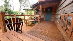 Un'area esterna in legno con una sedia e un tavolo, che conduce a un edificio con una porta blu.