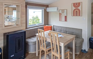 A compact living space with a kitchenette, a dining area, a sofa, and a TV.