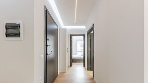 A modern hallway with a wooden floor, a built-in electrical panel, and a door leading to another room.