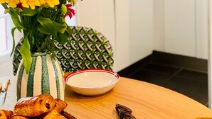Una cocina con armarios blancos, un jarrón de flores, un tazón y un plato.