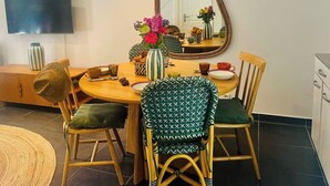 Un comedor con una mesa redonda, sillas, un espejo y un televisor en la pared.