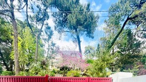 Un patio al aire libre con una mesa y sillas, rodeado por una cerca roja y follaje.