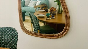 Una habitación con un espejo grande, una mesa de comedor con sillas, un sofá y una escalera al fondo.