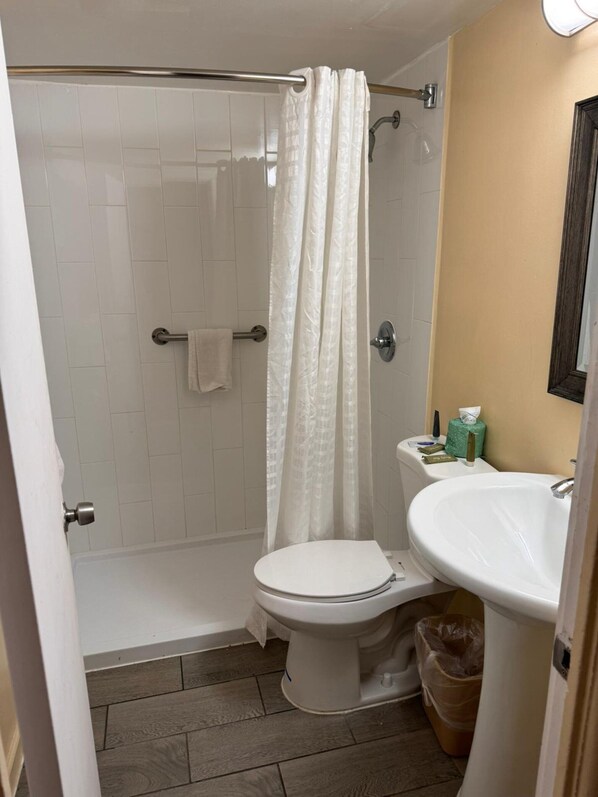 A bathroom with a shower, toilet, and sink. - The Boards AC (Atlantic City)