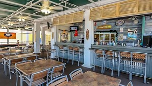 A restaurant with high ceilings, exposed beams, and a bar area with a counter and stools. Tables and chairs are arranged for dining. - Family Friendly Condo near Disney (Davenport)