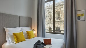 A hotel room with a large bed, two pillows, a book, and a handbag on the bed.