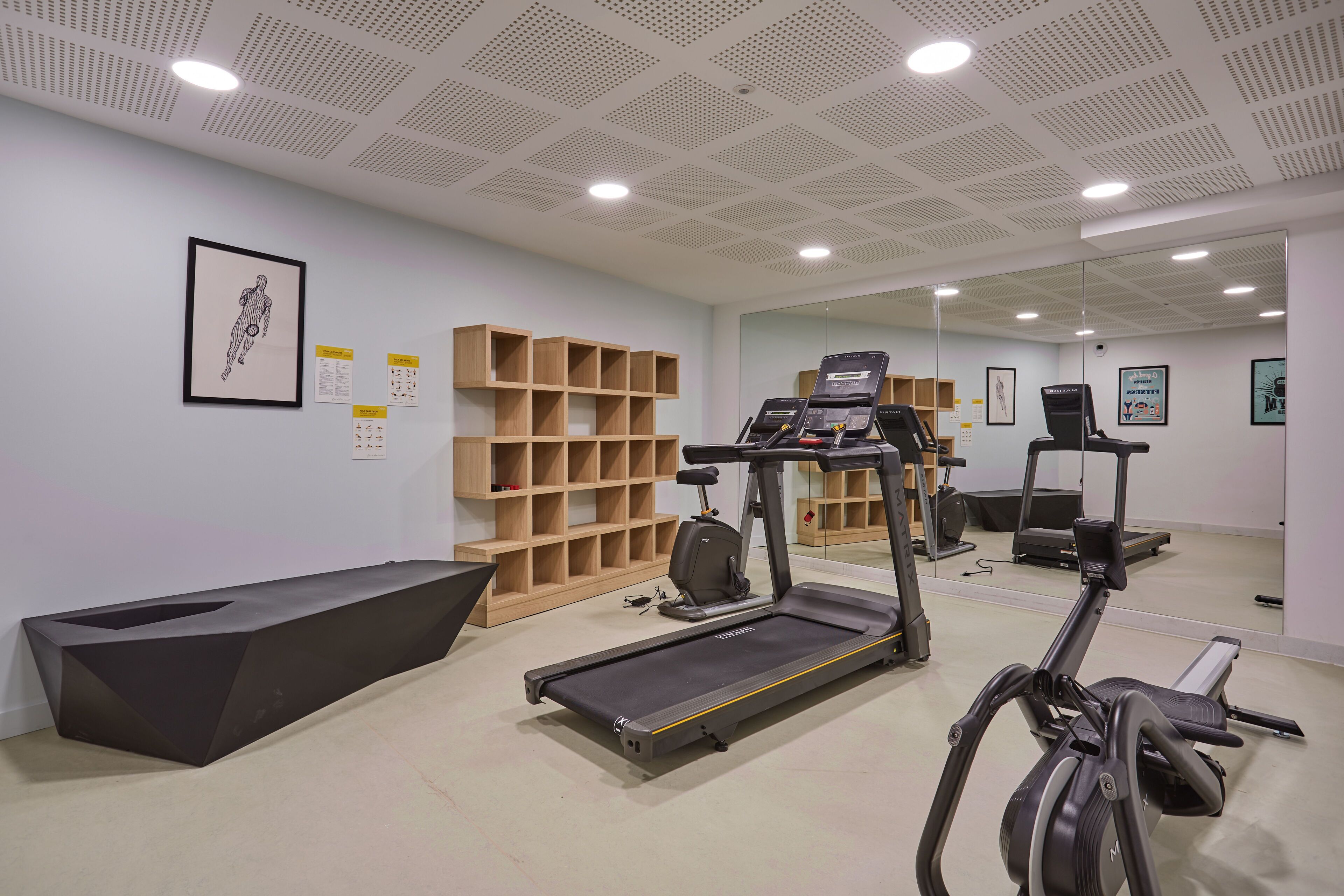 Un gimnasio moderno con cinta de correr, elíptica y un espejo grande.