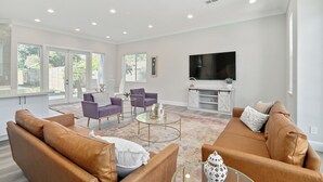 A modern living room with leather sofas, a coffee table, and a flat-screen TV.