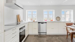 Una cocina moderna con armarios blancos, un lavavajillas de acero inoxidable y un horno empotrado.