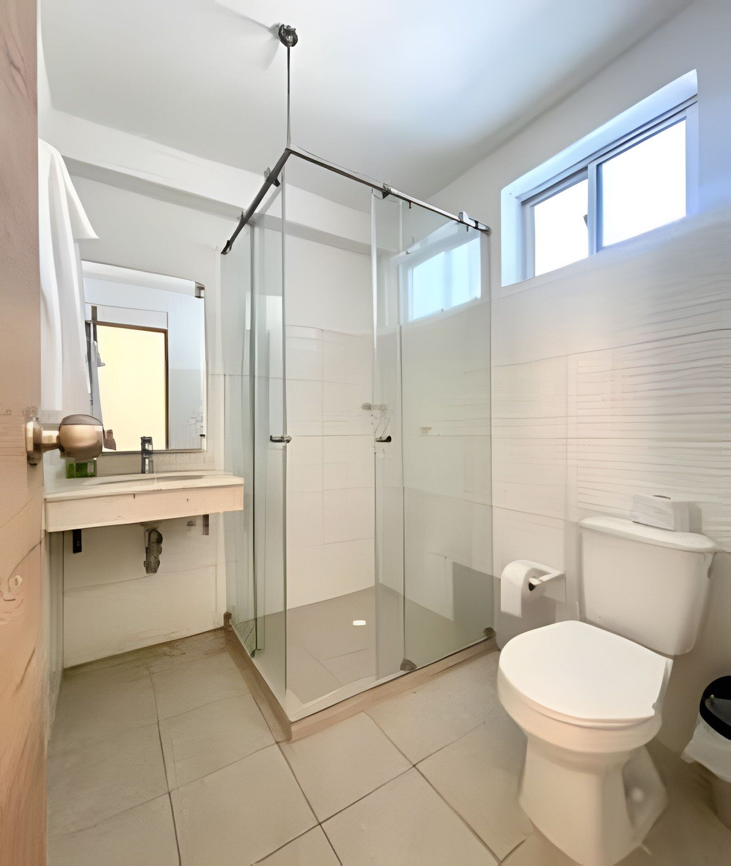 A modern bathroom with a glass shower enclosure, a toilet, and a sink with a mirror.