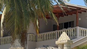 A resort with thatched umbrellas, lounge chairs, and a stone balustrade.
