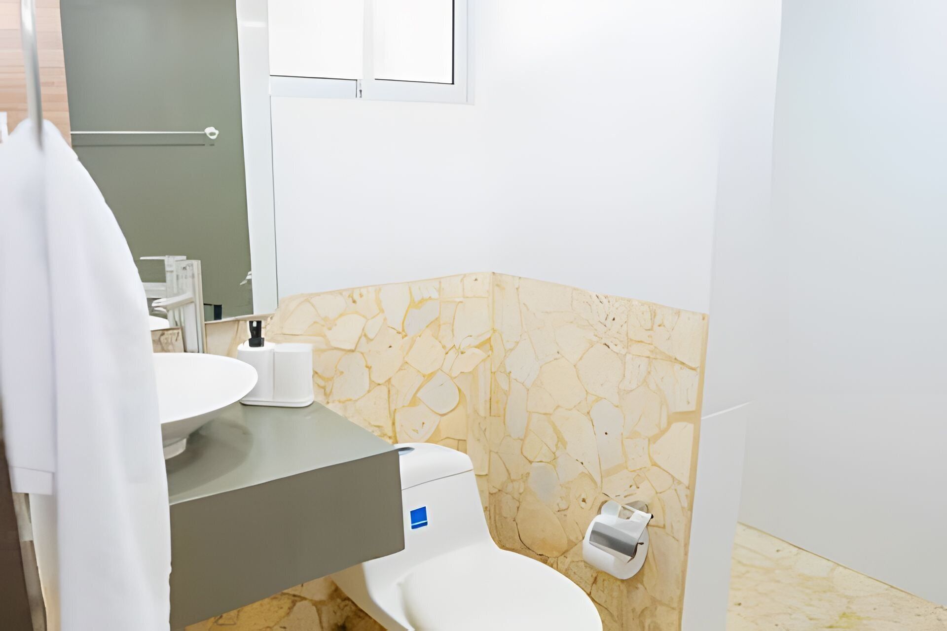 A bathroom with a white toilet, a sink, and a mirror.