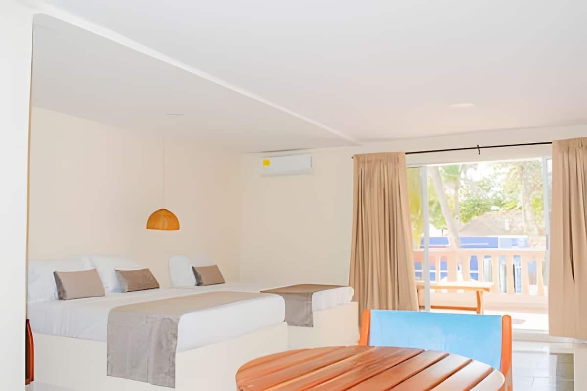 Ein Hotelzimmer mit Bett, einem kleinen Tisch und Blick ins Freie.