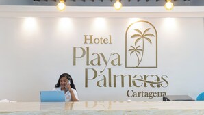 A reception desk with a sign for Hotel Playa Palmeras in Cartagena.