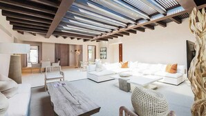 A spacious living area with a modern design, featuring a large sofa set, a coffee table, and a unique woven chair.