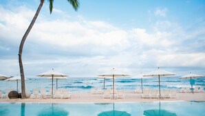 A poolside area with lounge chairs and umbrellas, overlooking the ocean.
