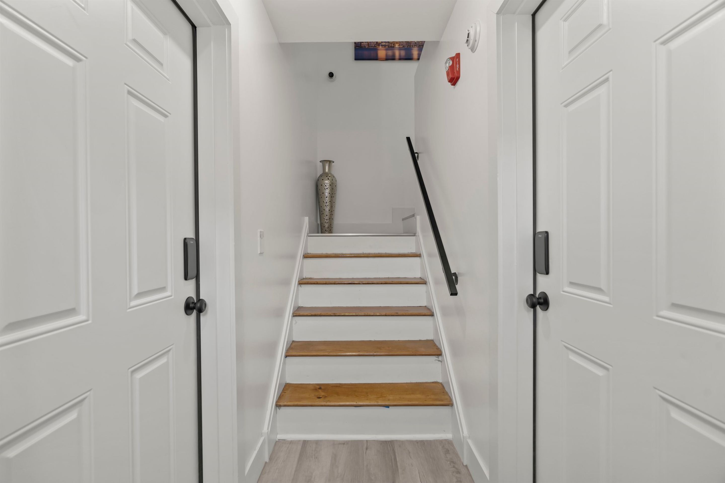 Eine Treppe mit weißen Wänden, einer Vase und einem Bild an der Wand.