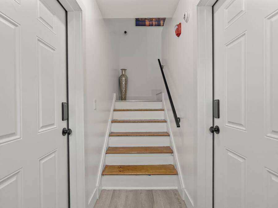 Eine Treppe mit weißen Wänden, einer Vase und einem Bild an der Wand.