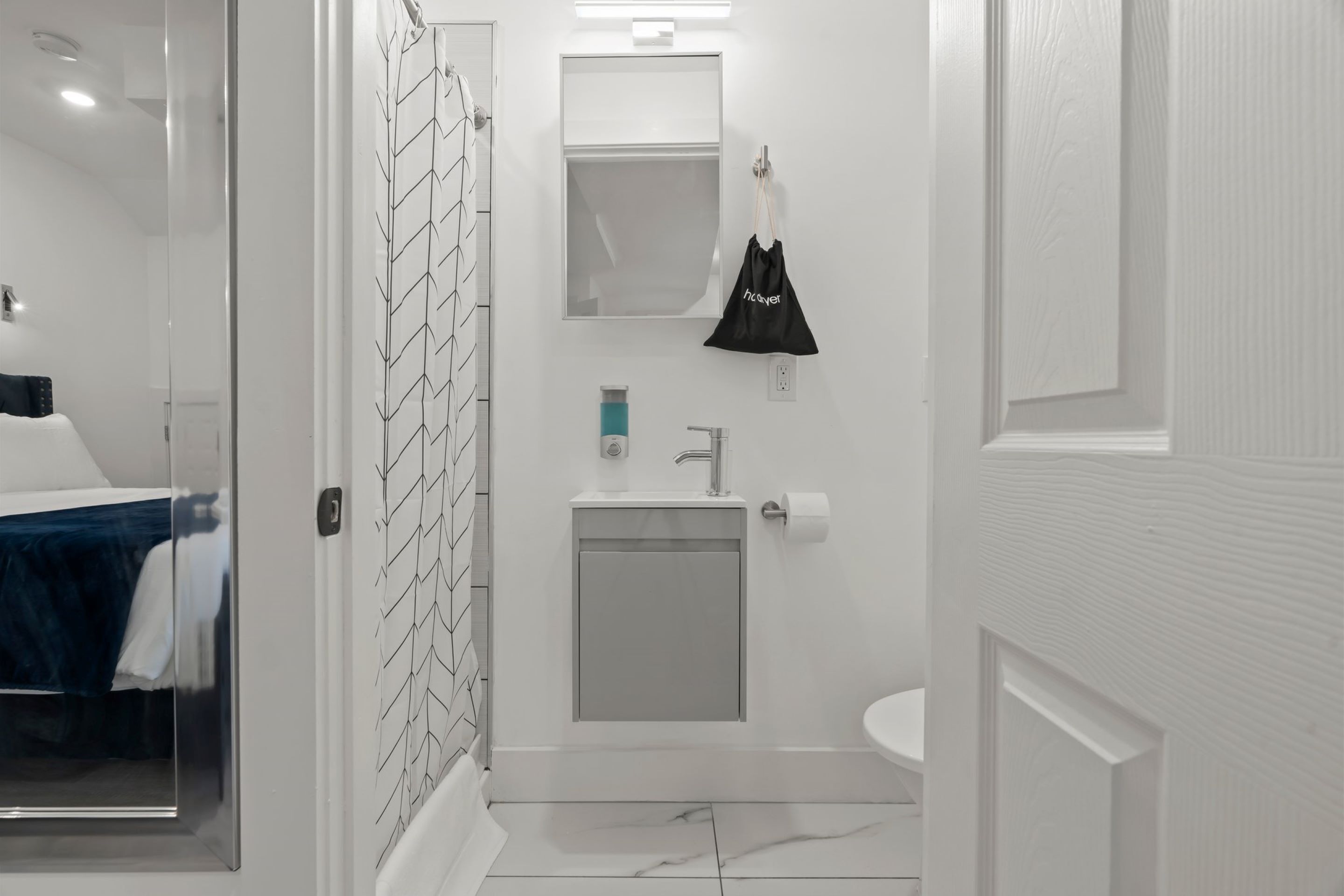 Ein modernes Badezimmer mit Duschkabine aus Glas, einem weißen Waschbecken und einem Spiegel darüber.