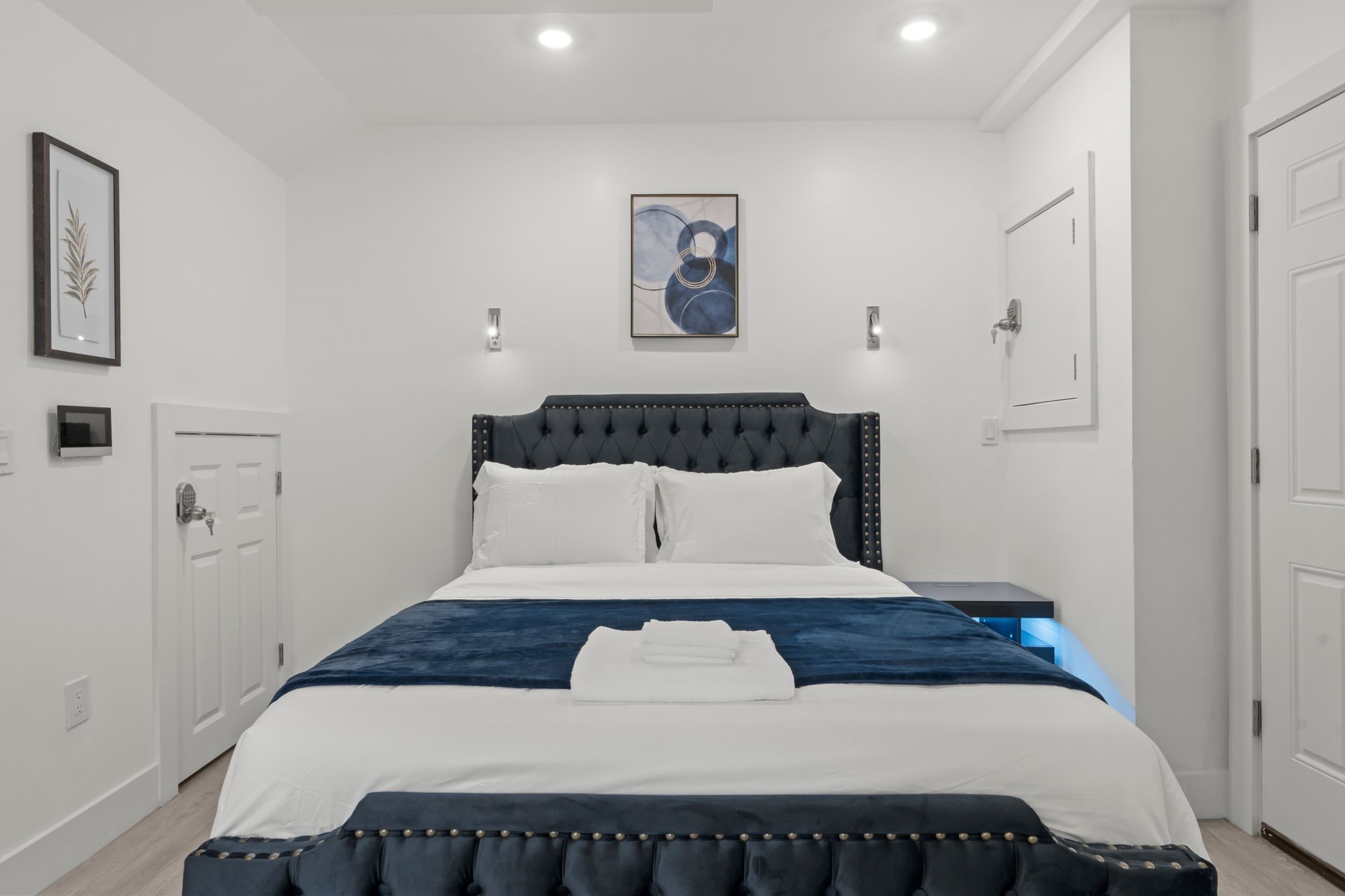 A neatly made bed with a dark headboard, white bedding, and a blue accent.