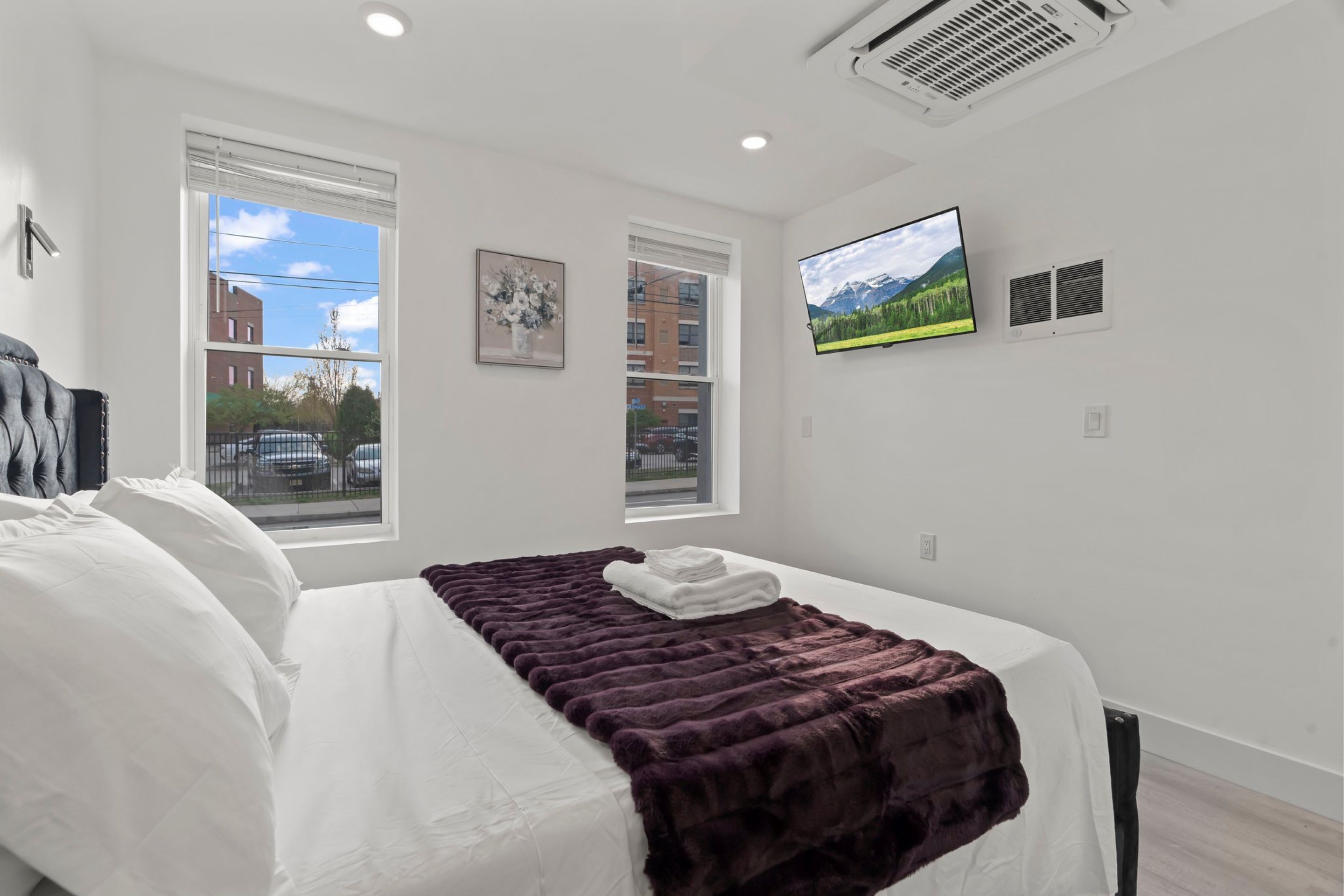 Una habitación de hotel moderna con una cama grande, un televisor de pantalla plana y una ventana con vistas a la ciudad.