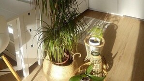 Una cocina con armarios blancos, un fregadero, una planta en maceta y una mesita de mimbre con velas.