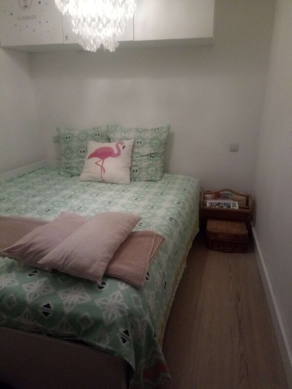 Une petite chambre à coucher, bien rangée, avec un lit, des oreillers, une table de chevet et une commode.