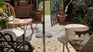 Un patio al aire libre con una mesa, sillas, un gran paraguas y plantas en macetas.