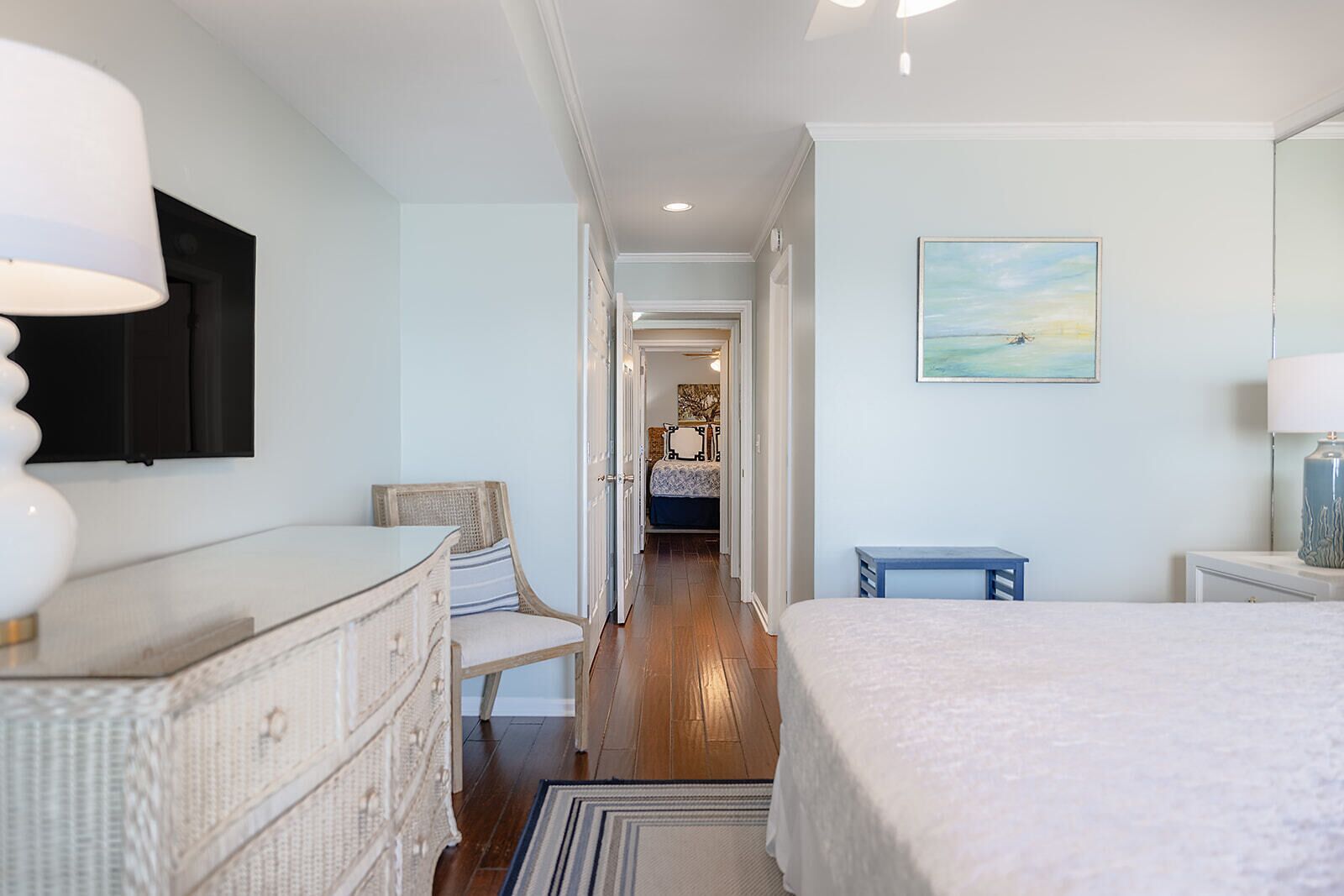 A bedroom with a bed, dresser, chair, and a painting on the wall.