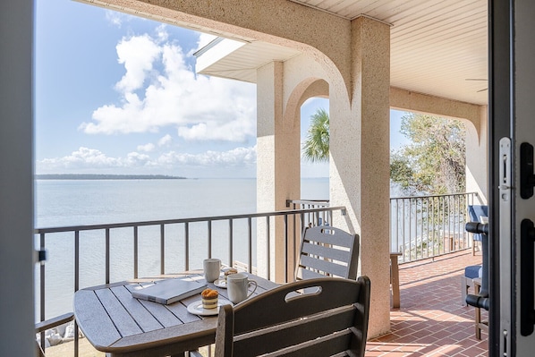 A balcony with a table and chairs, overlooking a body of water and a clear sky. - Ocean Pearl! Amazing Ocean & Pier Views, Oceanfront Pool, In the heart of the Pier Village! (Saint Simons Island)