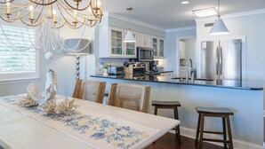 A modern kitchen with a central island, stainless steel appliances, and a chandelier. - Ocean Pearl! Amazing Ocean & Pier Views, Oceanfront Pool, In the heart of the Pier Village! (Saint Simons Island)