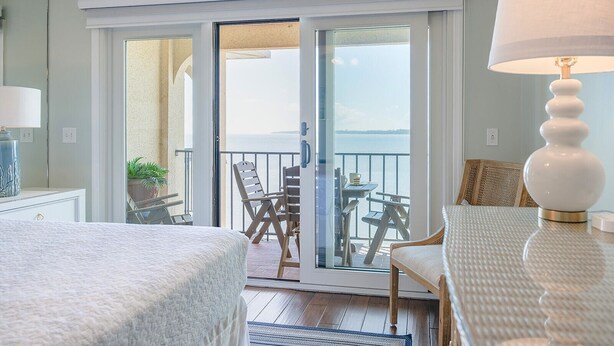 A hotel room with a balcony, a bed, a table, and a lamp. - Ocean Pearl! Amazing Ocean & Pier Views, Oceanfront Pool, In the heart of the Pier Village! (Saint Simons Island)