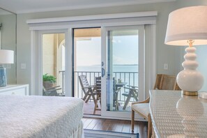 A hotel room with a balcony, a bed, a table, and a lamp. - Ocean Pearl! Amazing Ocean & Pier Views, Oceanfront Pool, In the heart of the Pier Village! (Saint Simons Island)