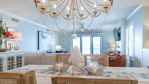 A dining area with a chandelier, a white fish sculpture, and a table set with candles and flowers. - Ocean Pearl! Amazing Ocean & Pier Views, Oceanfront Pool, In the heart of the Pier Village! (Saint Simons Island)