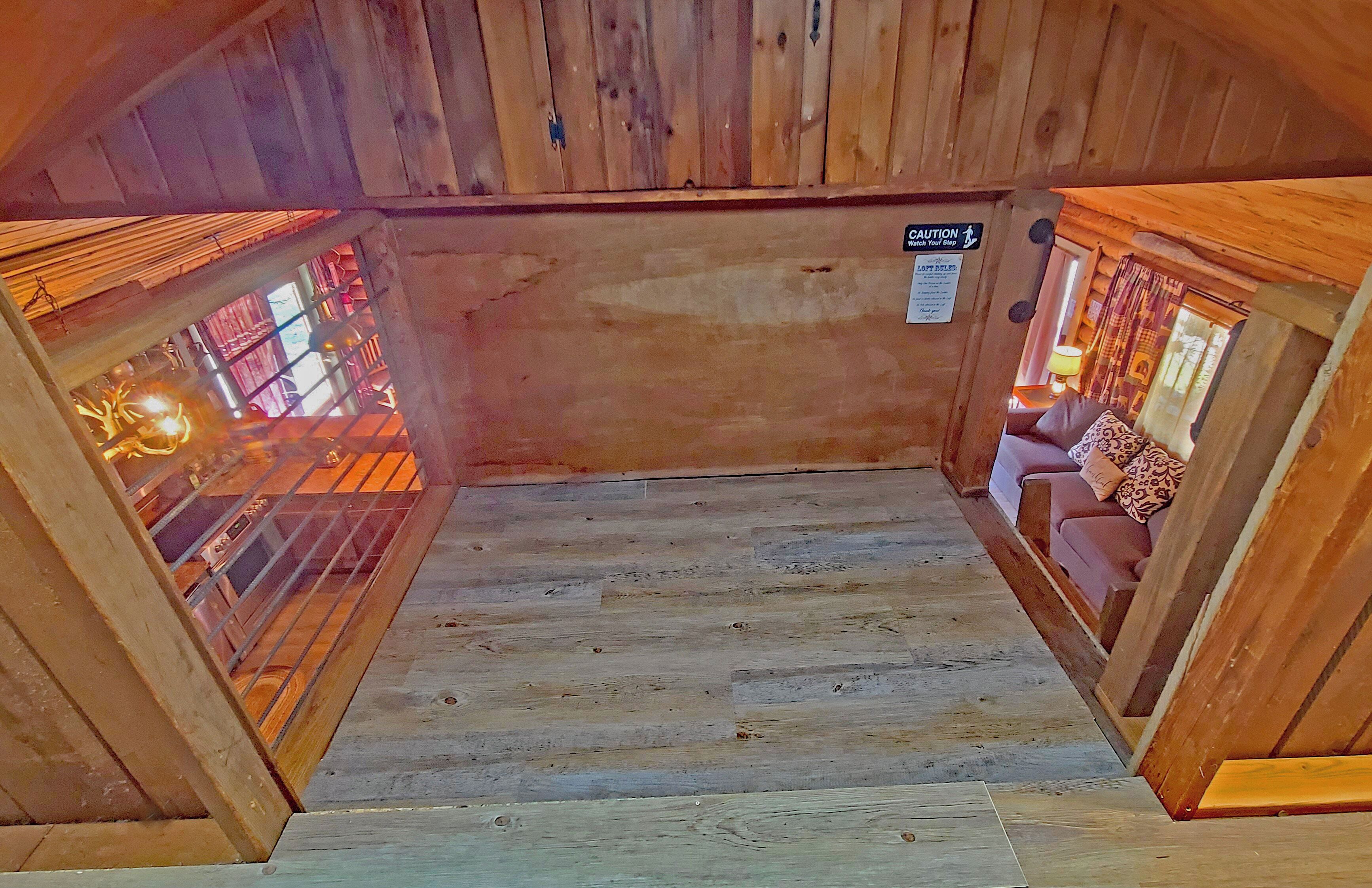 A wooden staircase leading to a room with a view of a metal gate and a sign indicating a caution area.