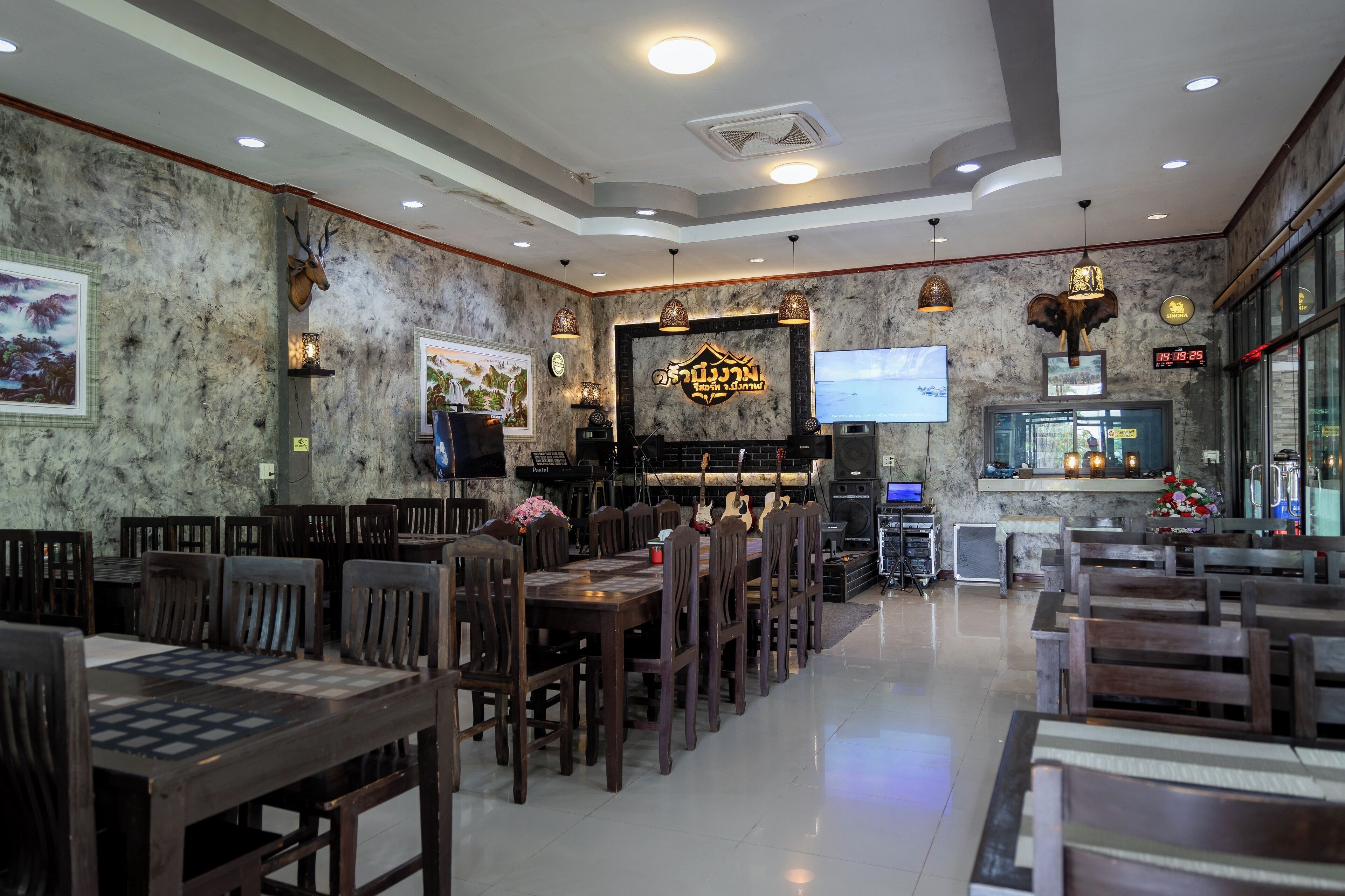 Un restaurante con mesas y sillas de madera, una zona de bar con televisor y decoración en las paredes.
