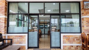 A restaurant with a brick exterior, large glass windows, and a wooden floor. - Buengngarm Resort (Bung Khong Long)