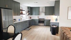 Eine moderne Küche mit dunklen Schränken, einem Edelstahlkühlschrank und einem eingebauten Backofen.