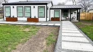 Ein modernes, zweistöckiges Haus mit einer überdachten Veranda und einem gepflasterten Weg zum Eingang.