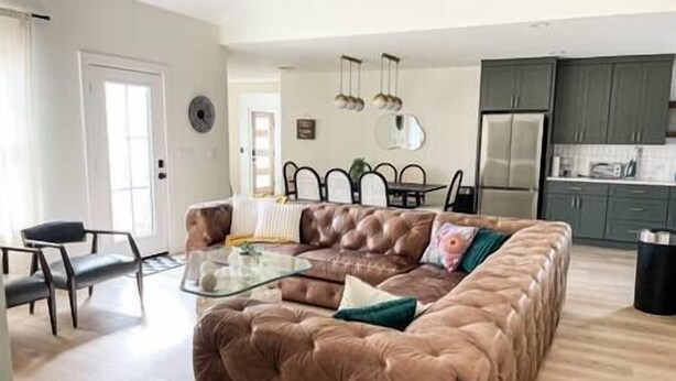 Ein Wohnzimmer mit braunem Ledersofa, einem Glastisch und einem Essbereich mit Tisch und Stühlen.
