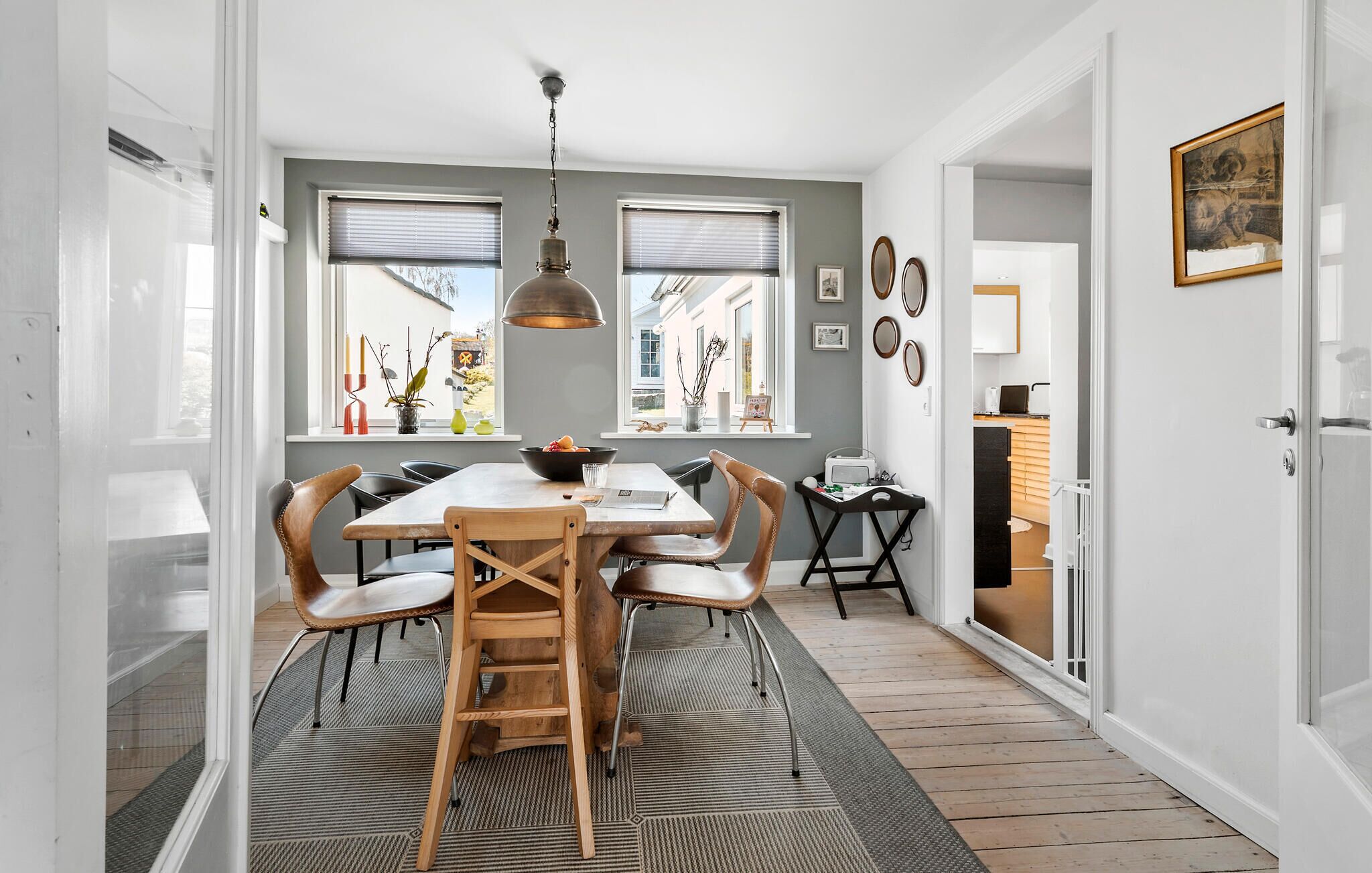 En matplats med ett träbord, stolar och en hängande lampa.