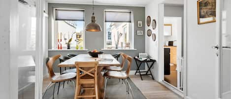 A dining area with a wooden table, chairs, and a hanging light fixture.